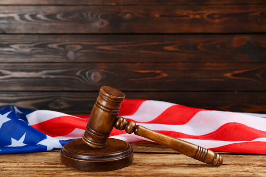 Wooden gavel and American flag on table