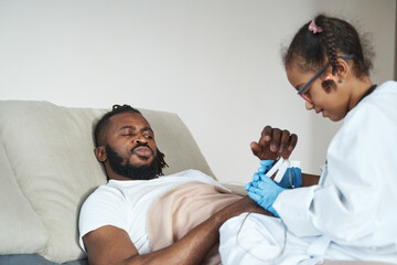Fototapeta premium African American girl in medical gown measures the indicators of a lying father