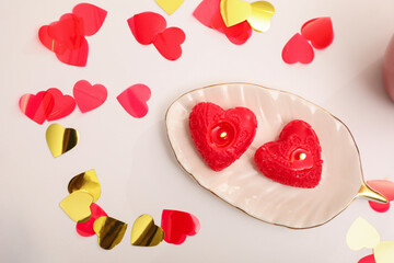 Red heart shaped candles and confetti on white table, flat lay. Valentine's Day celebration