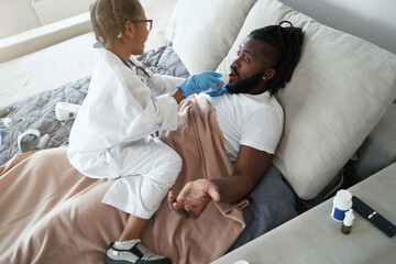 Obraz premium African American girl is giving medicine to her lying father