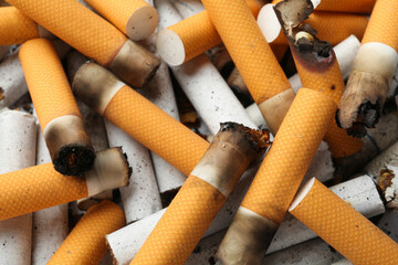 Pile of cigarette stubs as background, closeup view