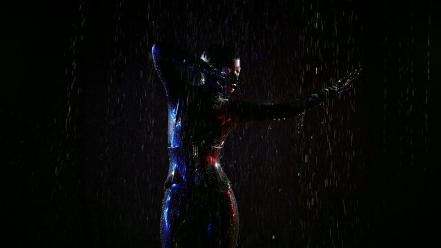 Woman in erotic latex BDSM domination clothes dancing in the rain in the dark