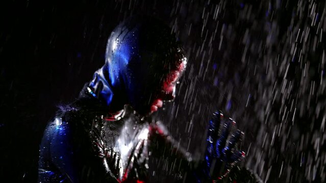 Close-up of a head fetish game of a woman in a black leather helmet with water jets on a dark background