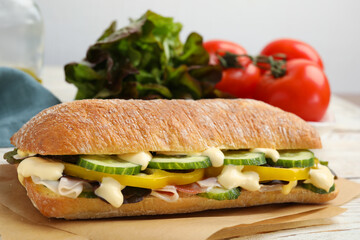 Delicious sandwich with vegetables, ham and mayonnaise on parchment paper, closeup