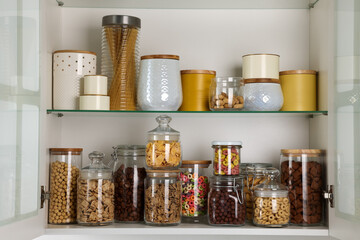 Glass containers with different breakfast cereals and other products on shelves