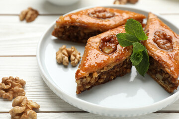Delicious sweet baklava with walnuts and mint on white wooden table, closeup