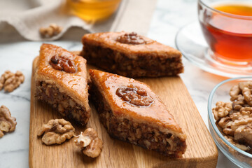 Fototapeta na wymiar Delicious honey baklava with walnuts served on white marble table, closeup