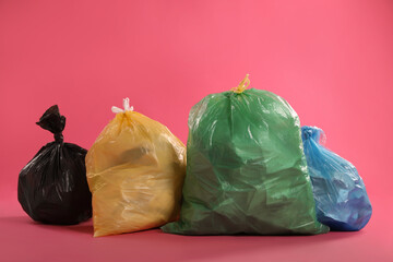 Trash bags full of garbage on pink background