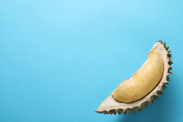 Piece of fresh ripe durian on light blue background, top view. Space for text