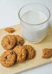 Chocolate chip cookies with glass of milk on wood plate and isolated white background. 