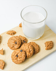 Chocolate chip cookies with glass of milk on wood plate and isolated white background. 