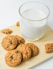 Chocolate chip cookies with glass of milk on wood plate and isolated white background. 