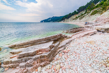 Pebbles beach colorful bay in Conero natural park dramatic coast headland rock cliff adriatic sea...