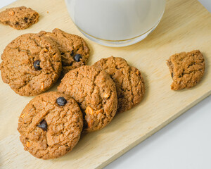 Chocolate chip cookies with glass of milk on wood plate and isolated white background. 
