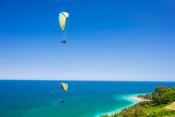 Paragliders flying over scenic coast line of the Conero natural, Italy. Extreme sport over dramatic coast headland in the mediterranean sea tourism destination