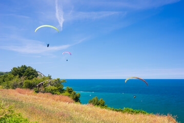 Paragliders flying over scenic coast line of the Conero natural, Italy. Extreme sport over dramatic...