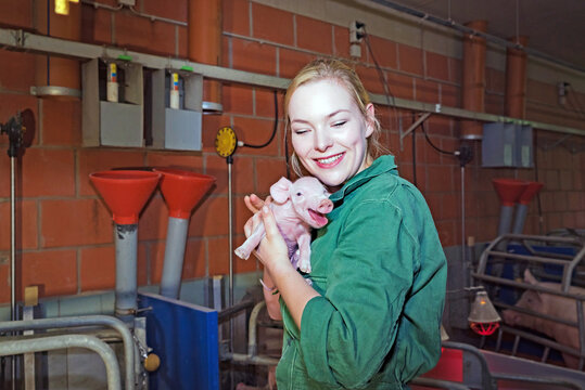 Spass an der Schweinehaltung - junge Frau mit einem kleinen Ferkel im Arm, Symbolfoto.