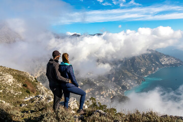 Happy couple standing at cliff with scenic view from Monte Comune on the coastal town Positano....