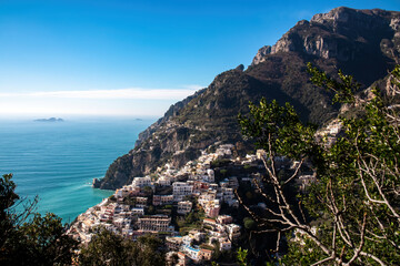Panoramic view on colorful houses of coastal town Positano, Amalfi Coast, Italy, Campania, Europe. Branch of tree in foreground. Vacation at coastline at Tyrrhenian, Mediterranean Sea. Path of Gods