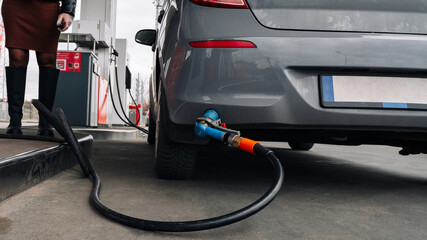 Gas station. Pump fuel petrol in tank car. Gasoline oil in nozzle. Close-up of the hand and the fuel gun. Blurred background.