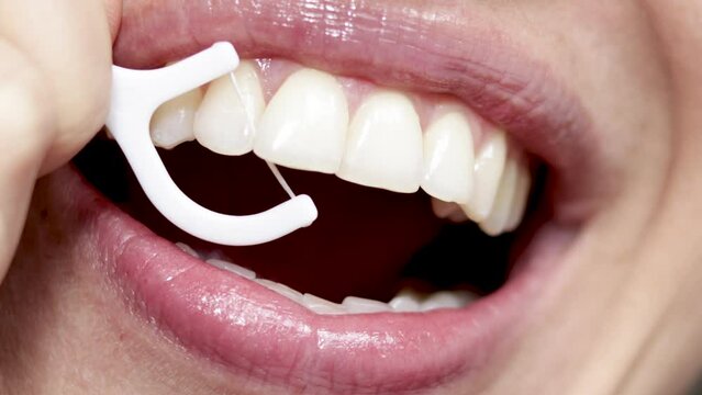 close up4 k video woman mouth smiling and flossing her teeth with white plastic toothpick. beautiful sexy smile, lips.natural teeth. dental care concept. oral hygiene, daily routine,procedures.