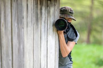 Female paparazzi detective taking pictures from the hide.
