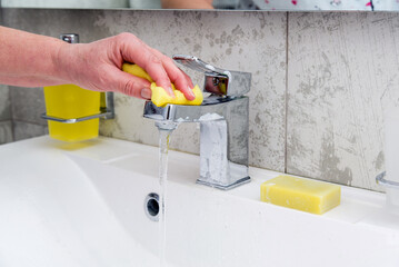 woman cleans a faucet in the bathroom.