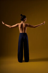 Back view of slim, flexible female practicing yoga at studio. Brunette girl with bare back...