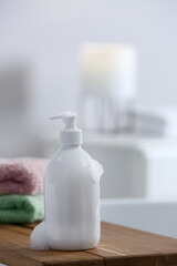 Obraz na płótnie Canvas Bottle of bubble bath with foam and towels on tub in bathroom