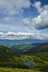Fototapeta premium Above view of high-altitude lakes, while sun catching mountain peaks in summer morning. Panoramic view of remote mountain valley with sun glare over clear calm lakes outdoor. Concept of landscape.