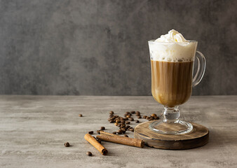 Black coffee with air cream on a dark brown wooden stand. Coffee beans and cinnamon straws on the...