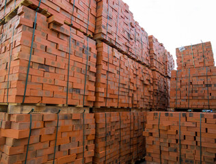 Pallets with red bricks are stored in an open area
