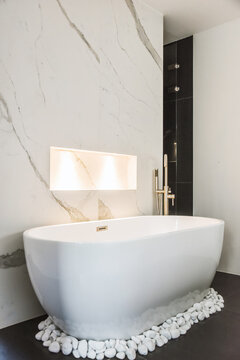 Modern bathroom with white bathtub surrounded with white stones