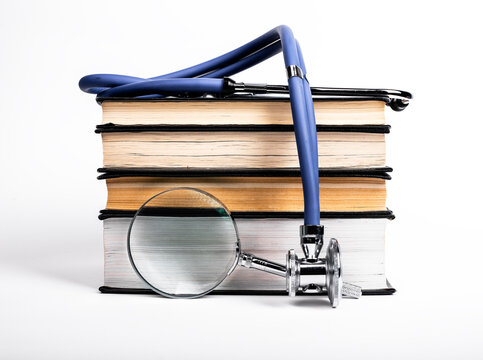 Books stack with stethoscope and magnifying glass. Medical data search and learning, preparing for examination, conducting research in medicine area. High quality photo