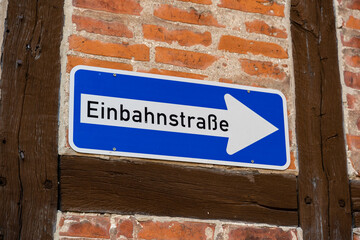 One way street traffic sign on a house wall in German language. Road sign of a white arrow on a...