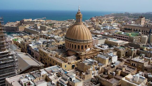 Aerial 4K footage of a drone flight over of Basilica Lady of Mount Carmel church, St. Paul's Cathedral in the old town of Valetta, Malta. Roofs of Malta capital from above on a sunny day