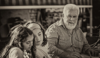 Grandparents and grandchildren playing together outdoor on a sunny afternoon at table games.