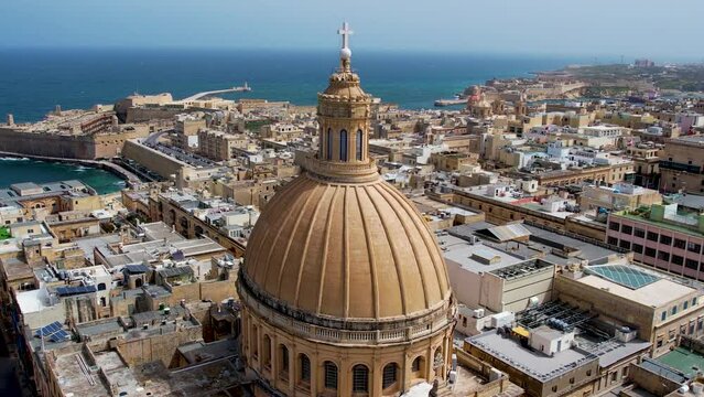 Aerial 4K footage of a drone flight over of Basilica Lady of Mount Carmel church, St. Paul's Cathedral in the old town of Valetta, Malta. Roofs of Malta capital from above on a sunny day