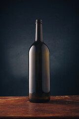 Wine bottle without label, no brand mockup on dark wooden background. Alcohol drink, vertical close up shot