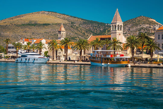 Moored ships and waterfront promenade with palms in Trogir, Croatia