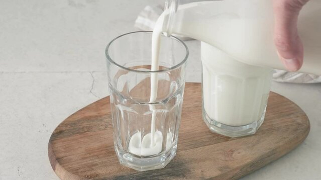 Pouring kefir or yogurt into a glass from a bottle. Healthy fermented milk drink. View from above. 4k video. Cold refreshment drink