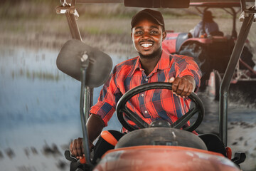 African farmer working and driving tractor in farm during harvest in countryside. Agriculture or...