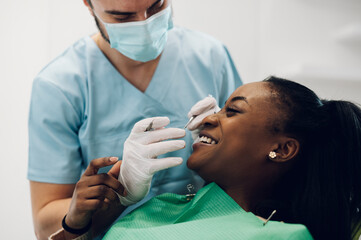 Dentist providing dental care treatment to a african american female patient