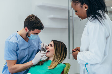 Obraz premium Woman patient in dental clinic being examined by a male dentist