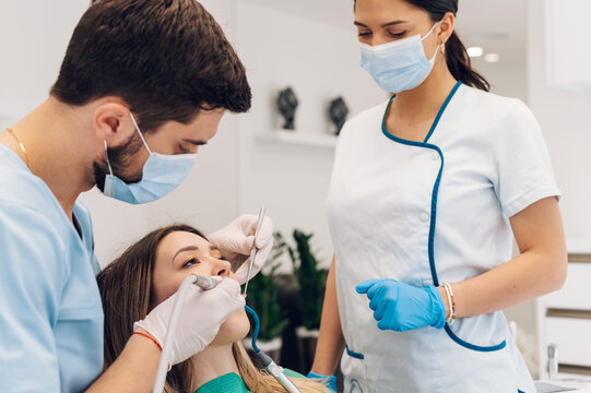 Woman patient in dental clinic being examined by a male dentist