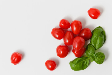 Cherry tomatoes with green basil on white background.