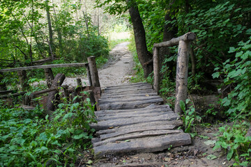 Landscape with old wooden bridge over the river surrounded by beautiful forest