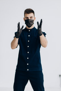 Male Doctor In Black Gloves Puts On Mask Against Covid