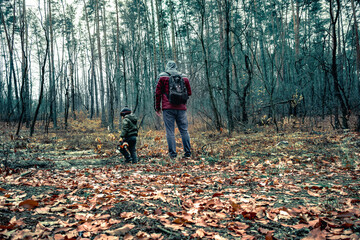 Fototapeta premium A man and a little boy are looking for a way in the forest. A father and son are walking through a dense forest