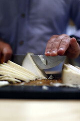 manos cortando queso con un cuchillo en la tabla de corte